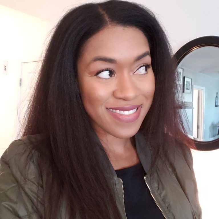 Woman in green jacket smiling and looking away from the camera.