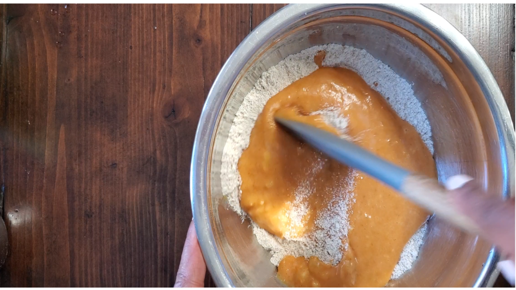 Wet orange mixture being added to dry baking mixture