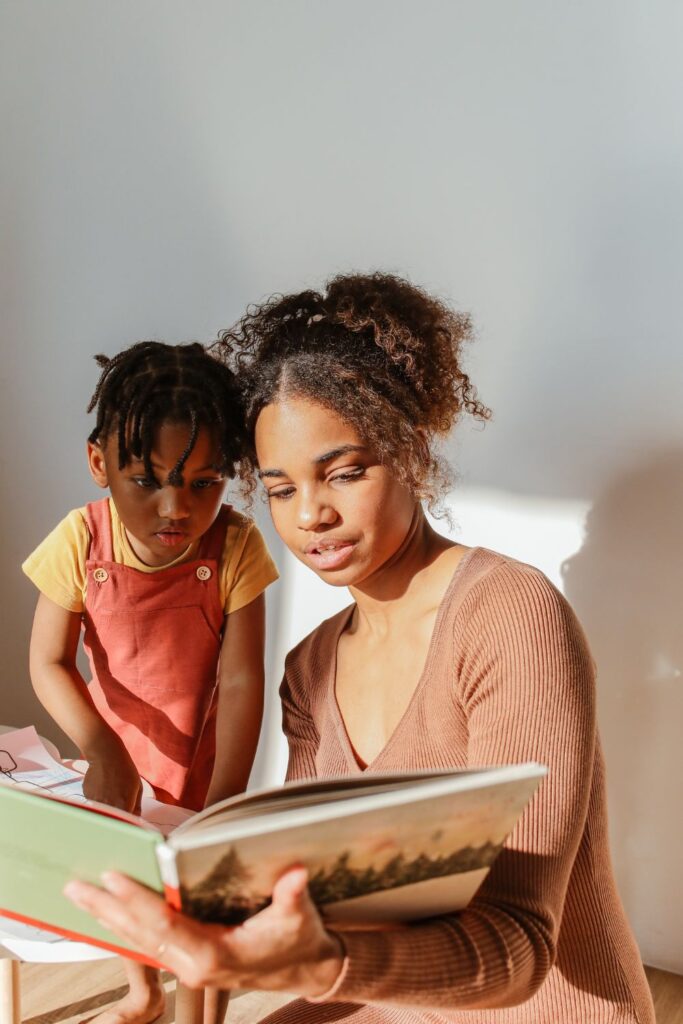 Woman reading a book to a small child in a calm manner. 