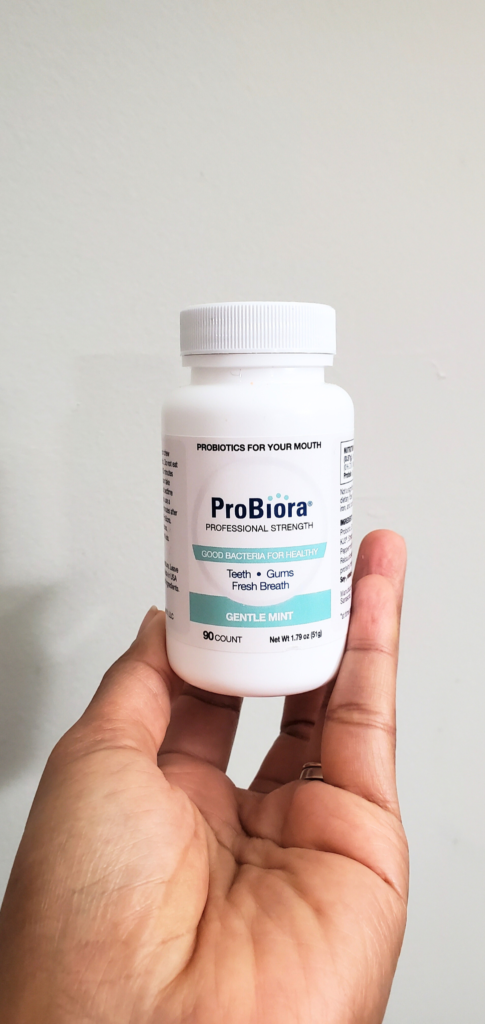 a hand holding a white supplement bottle Probiora probiotics for your mouth style and stewardship blog