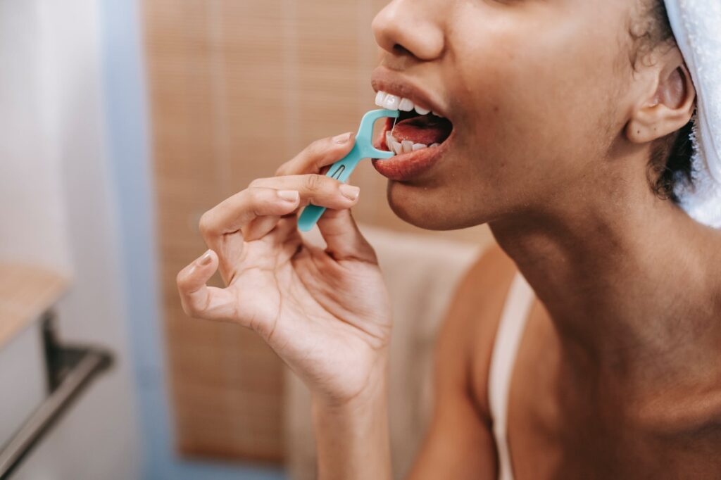 woman cleaning teeth with dental floss