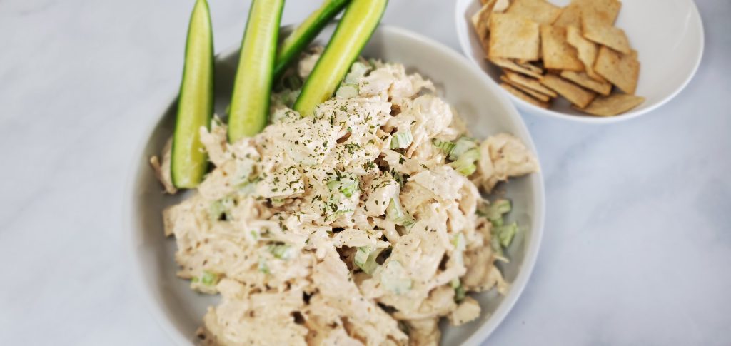 Large white plate with chunky chicken salad and pickle spears.