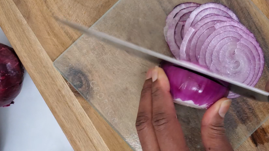 cutting board and red onion being sliced into slices