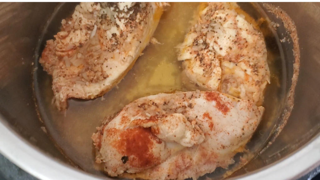 three cooked chicken breasts in the steel pot of the Instant pot pressure cooker