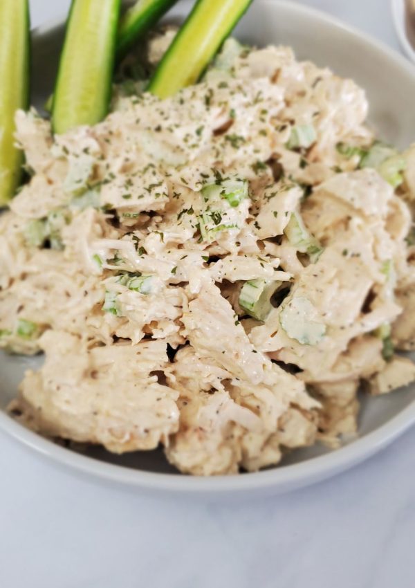 Large white plate with chunky chicken salad and pickle spears.