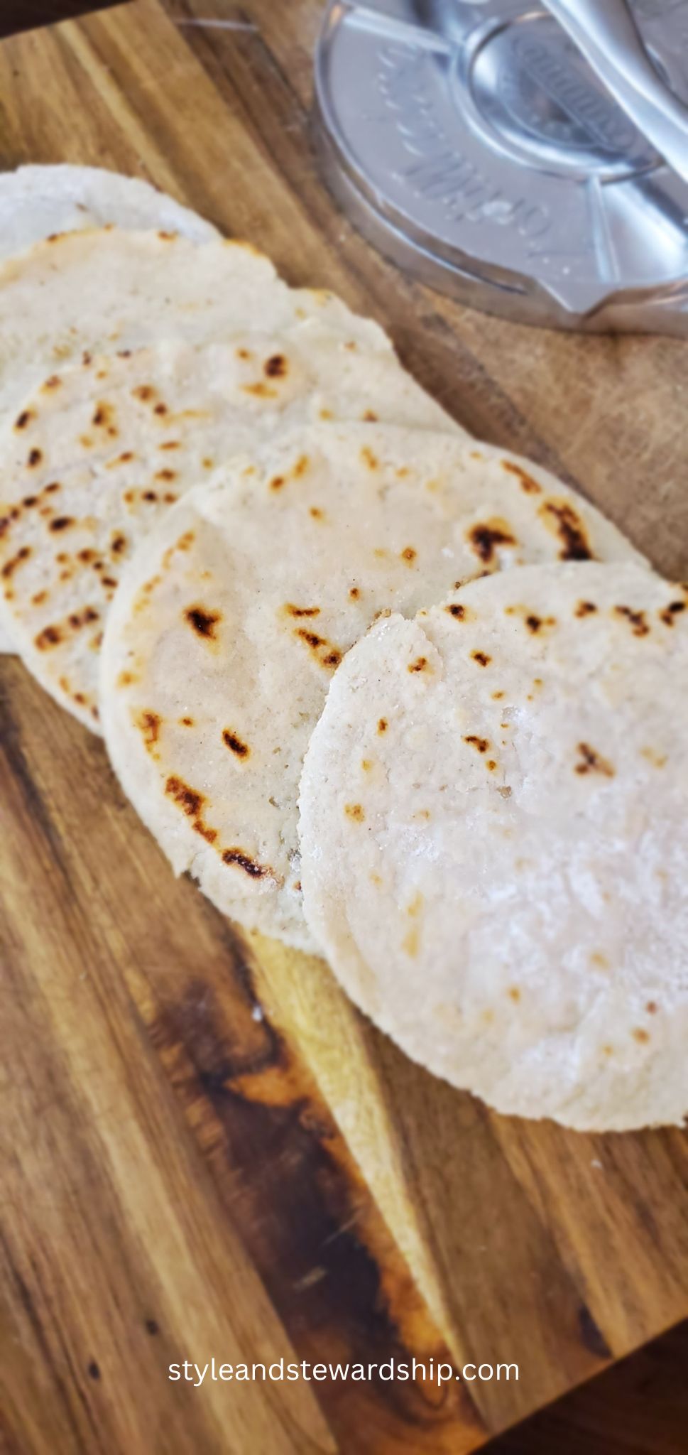almond flour tortillas on wooden cutting board with a metal tortilla press in the background style and stewardship dot com