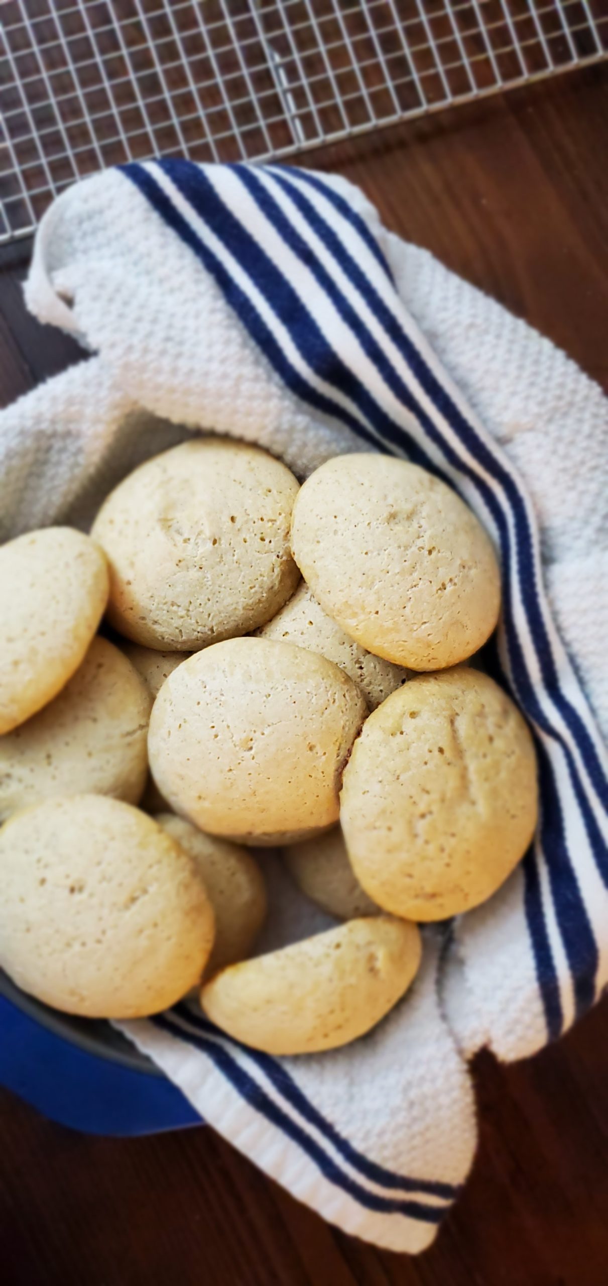 Blue-rimmed pan with a striped blue kitchen towel filled with golden dinner rolls