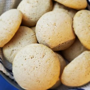 dinner rolls piled on top of a blue striped kitchen towel