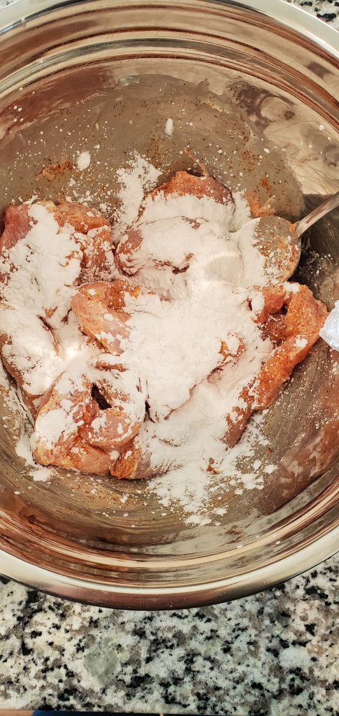 A stainless steel bowl with cut up chicken and topped with tapioca flour.