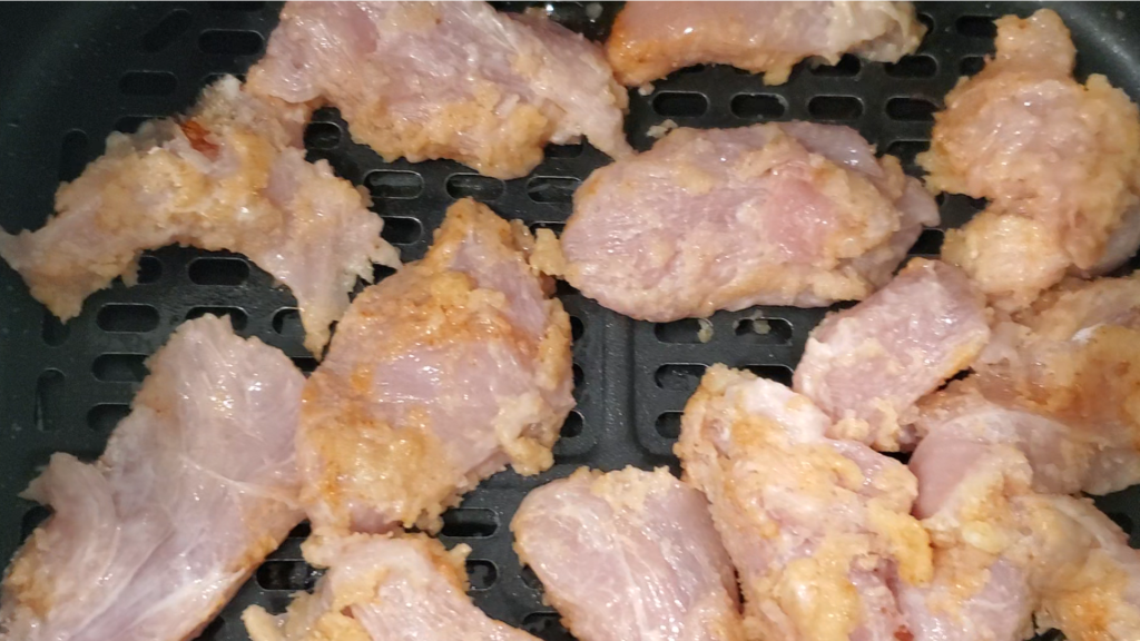 Coated chicken added to an air-fryer basket.