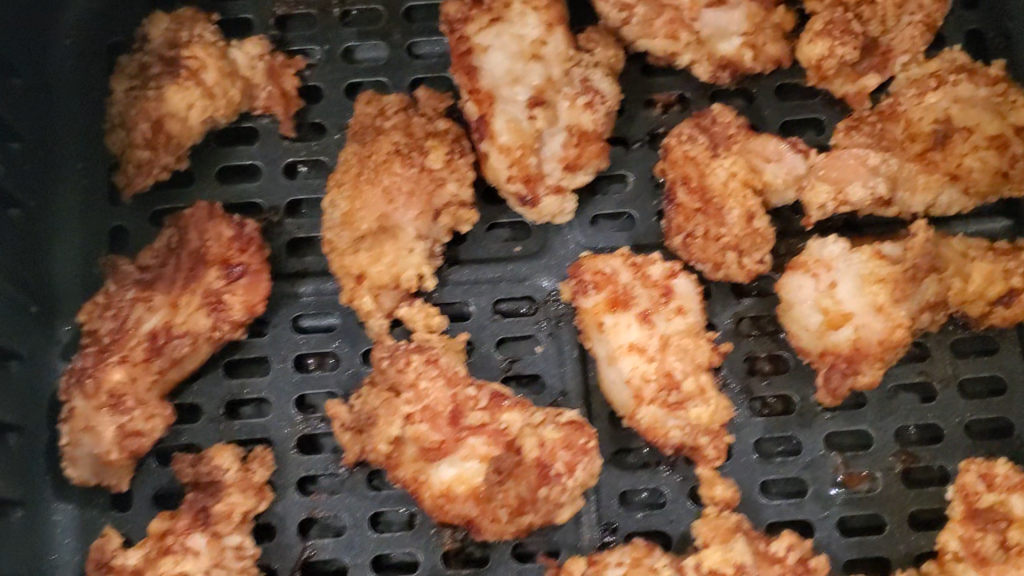 Golden grain free chicken nuggets in the basket of an air-fryer. style and stewardship dot com