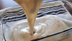 dairy free ice cream mixture being added to a glass dish