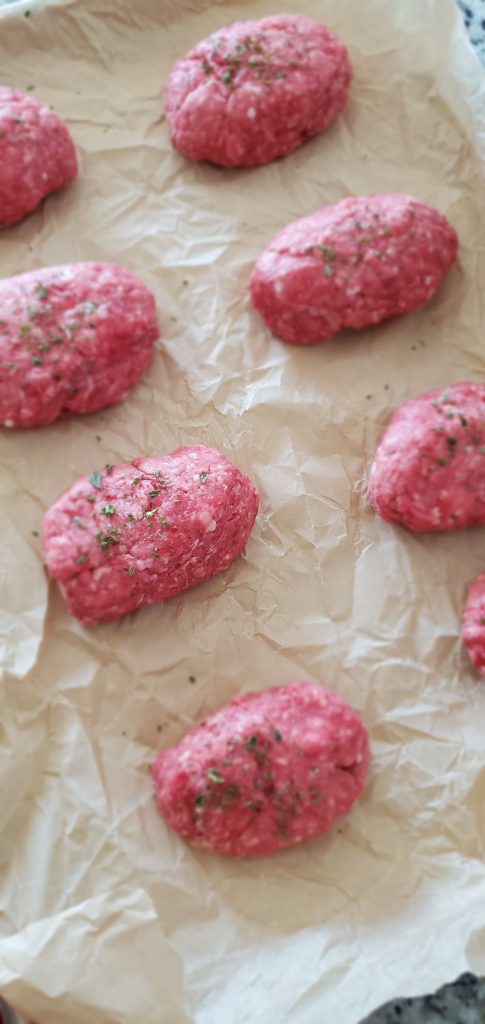 Eight small meat loaves sprinkled with parsley on top of parchment paper