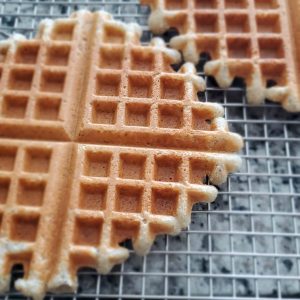Wire rack with 3 large golden brown waffles on top style and stewardship dot com