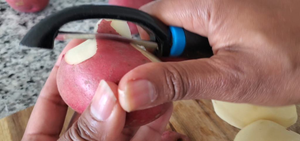peeling red skinned potatoes with a vegetable peeler