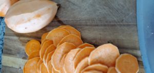 sweet potato slices laying in a pile on a wooden cutting board