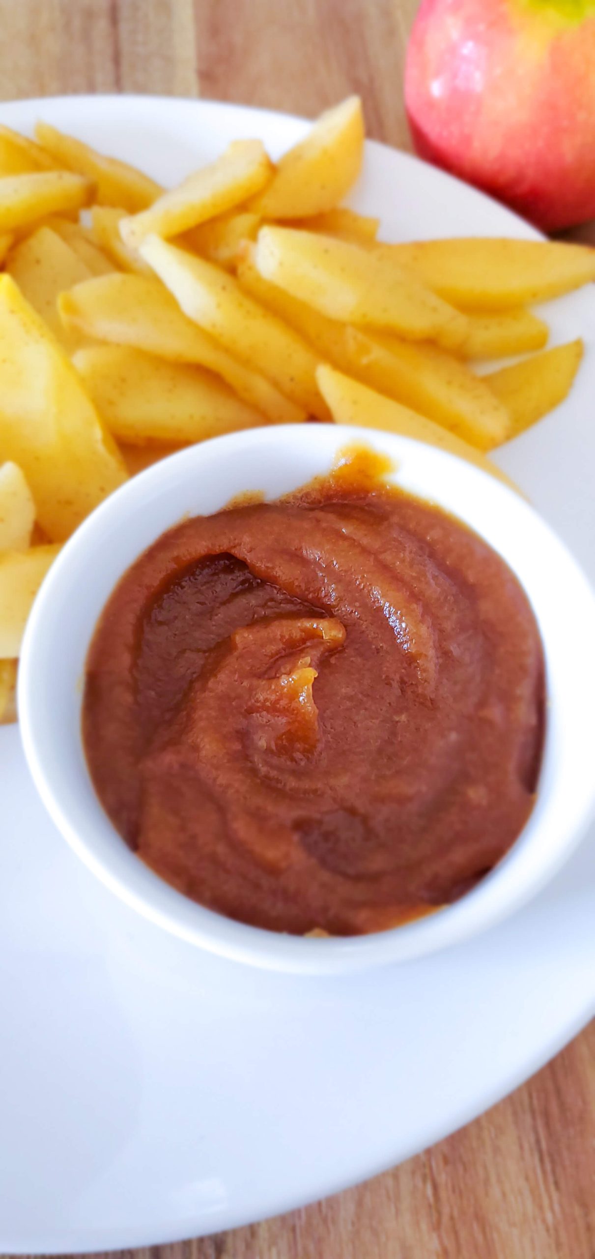 Caramel date dip in a small white bowl and sliced apples on a white plate