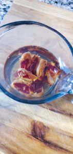 Dates in a glass measuring cup soaking in water