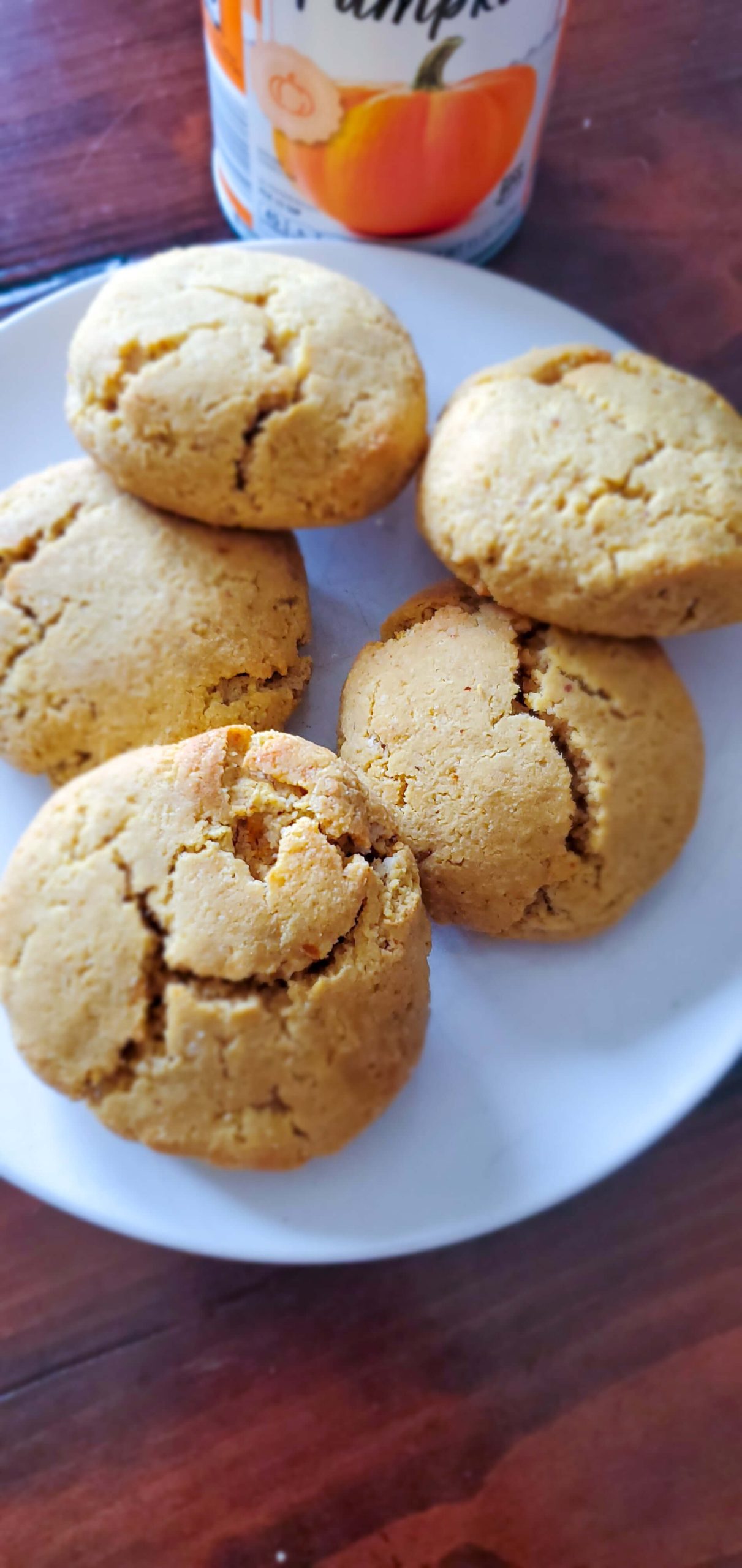 A white plate with five biscuits and a can of pumpkin puree is pictured behind.