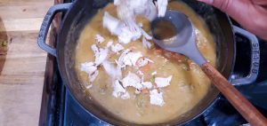 chicken being added to a skillet with gravy mixture