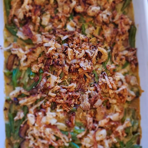 Large white rectangle casserole dish with green beans, creamy sauce, and golden onions on top.