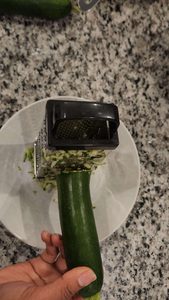 zucchini being grated into a bowl