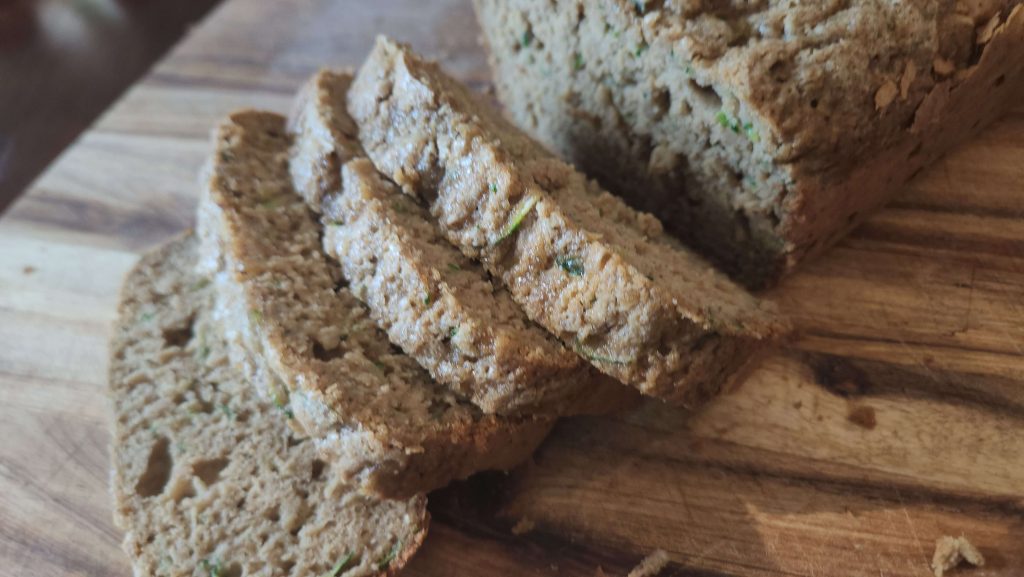 wooden cutting board with a loaf of zucchini bread in slices