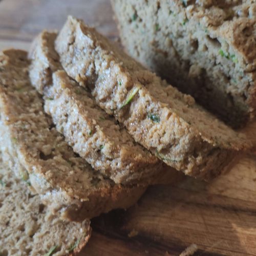 wooden cutting board with a loaf of zucchini bread in slices