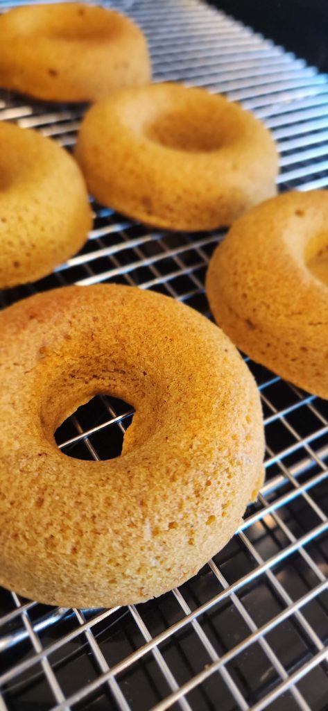 Baked gluten free doughnuts cooling on a silver rack