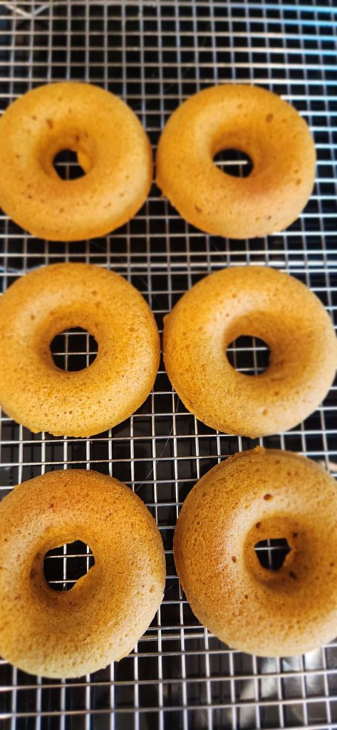 A silver rack with six baked pumpkin doughnuts.